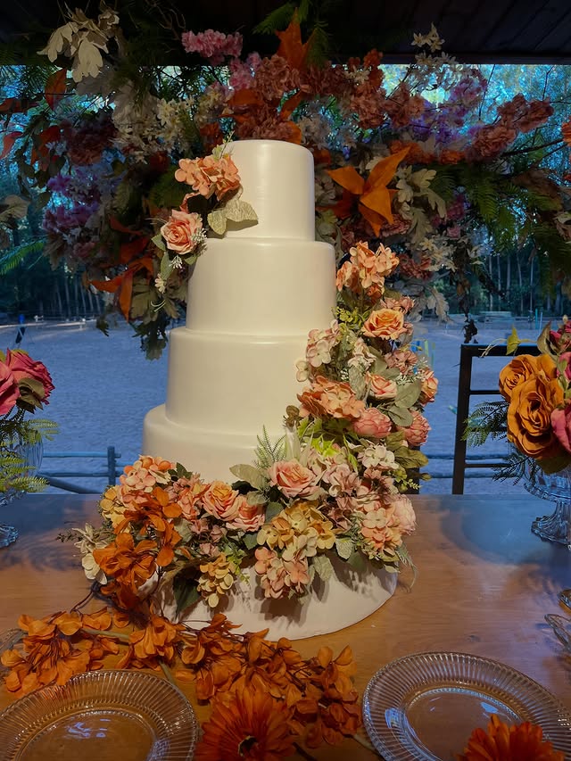 Bolo de casamento cercado por flores em tons de outono